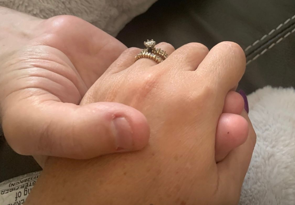 Hands clasped in support — illustrative caregiver motif.